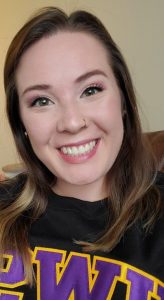 Sierra Huss, new Rentals Specialist, smiles at the camera in a black sweatshirt with the purple and gold University of Stevens Point logo. 